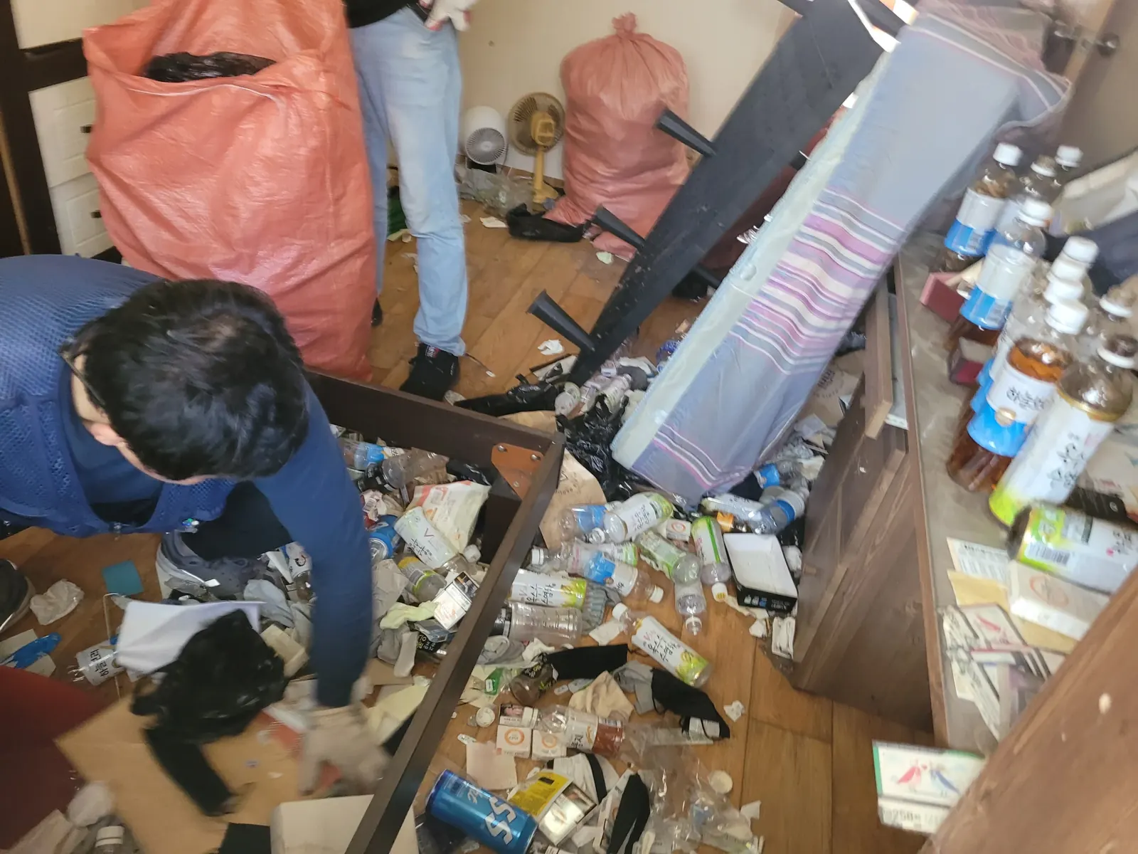 인천 쓰레기집청소 관련 현장: 작업자가 포대에 물품을 담아 정리하는 모습