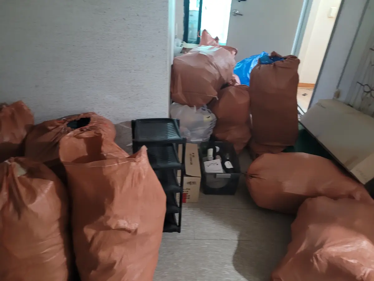 생활쓰레기 봉투가 복도에 쌓여 있는 정리 전 현장 모습